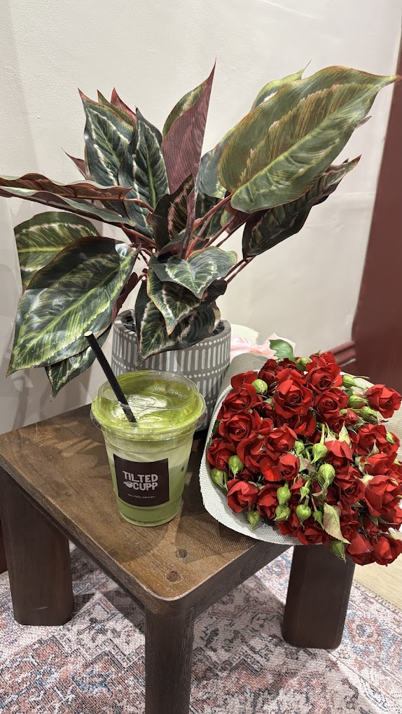 Iced matcha on a wooden stool next to red roses